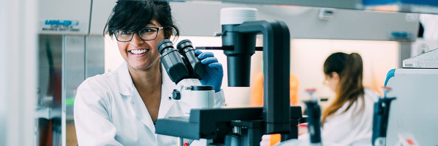 Scientist standing at a microscope in the lab