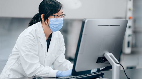 Scientist in the lab looking at a computer, participating in live virtual training on neural induction.